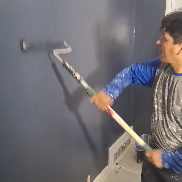 Deep navy sample color rolled onto a real wall during an interior repaint